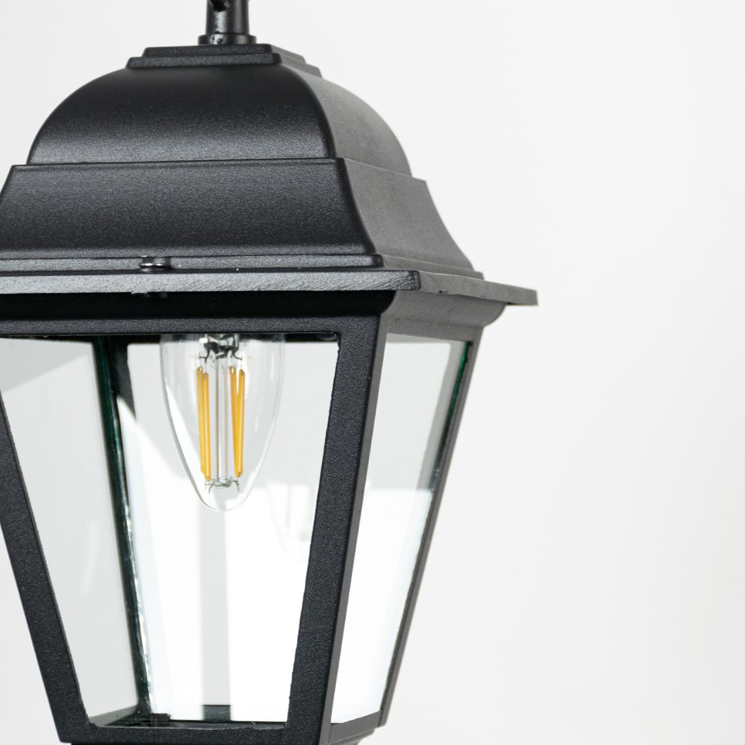 Closeup of outdoor hanging lantern light showing bulb detail and refined black metal finish.