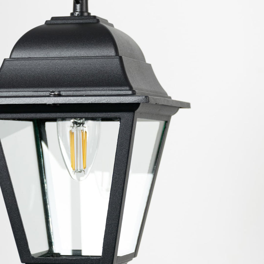Closeup of outdoor hanging lantern light showing bulb detail and refined black metal finish.