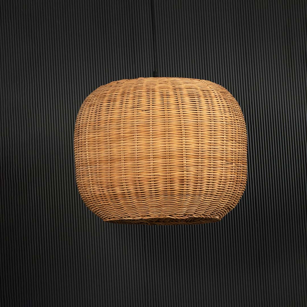 Round rattan pendant light on black background highlighting its natural handcrafted weave.