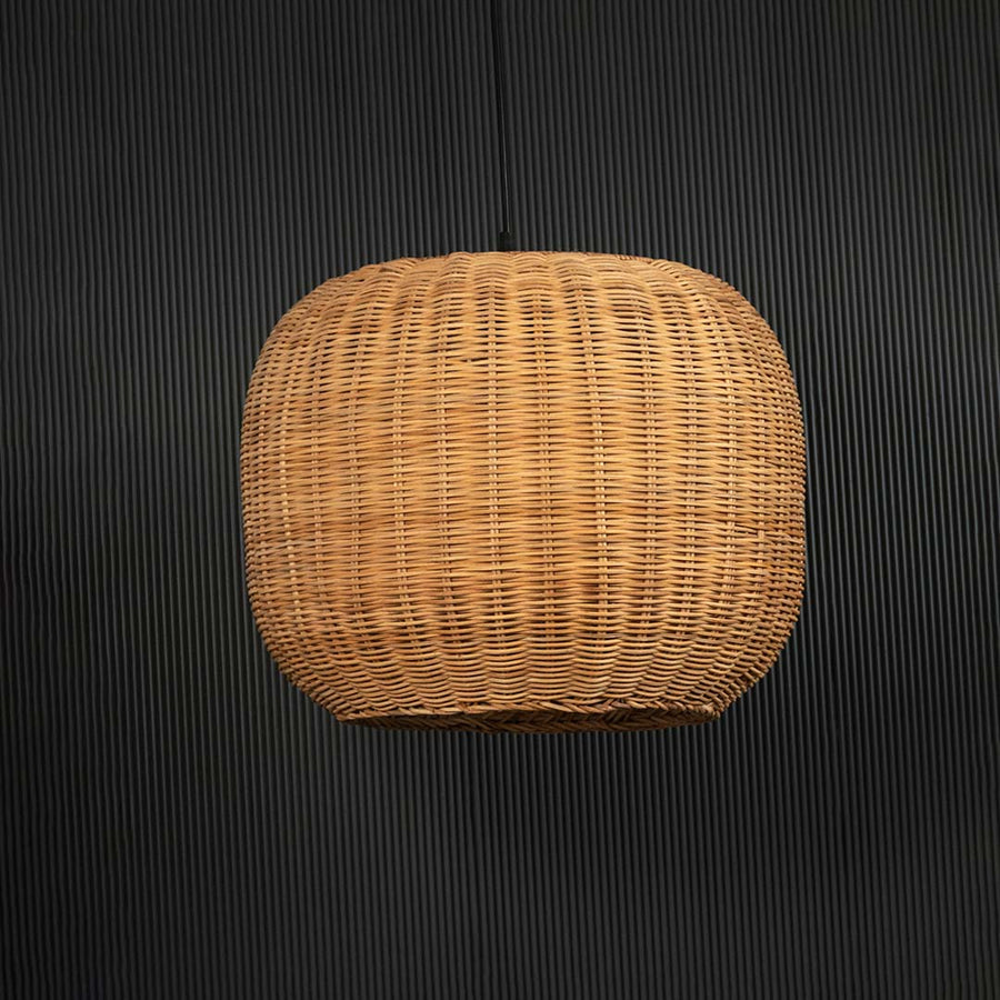 Round rattan pendant light on black background highlighting its natural handcrafted weave.