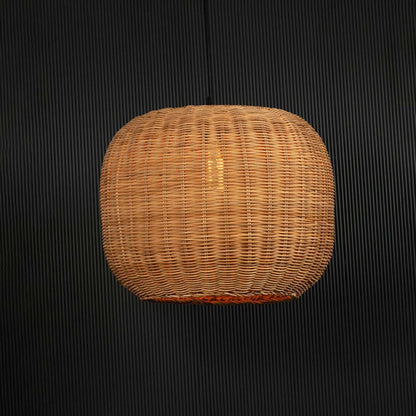 Round rattan pendant light glowing softly on black background creating a cozy ambient effect.