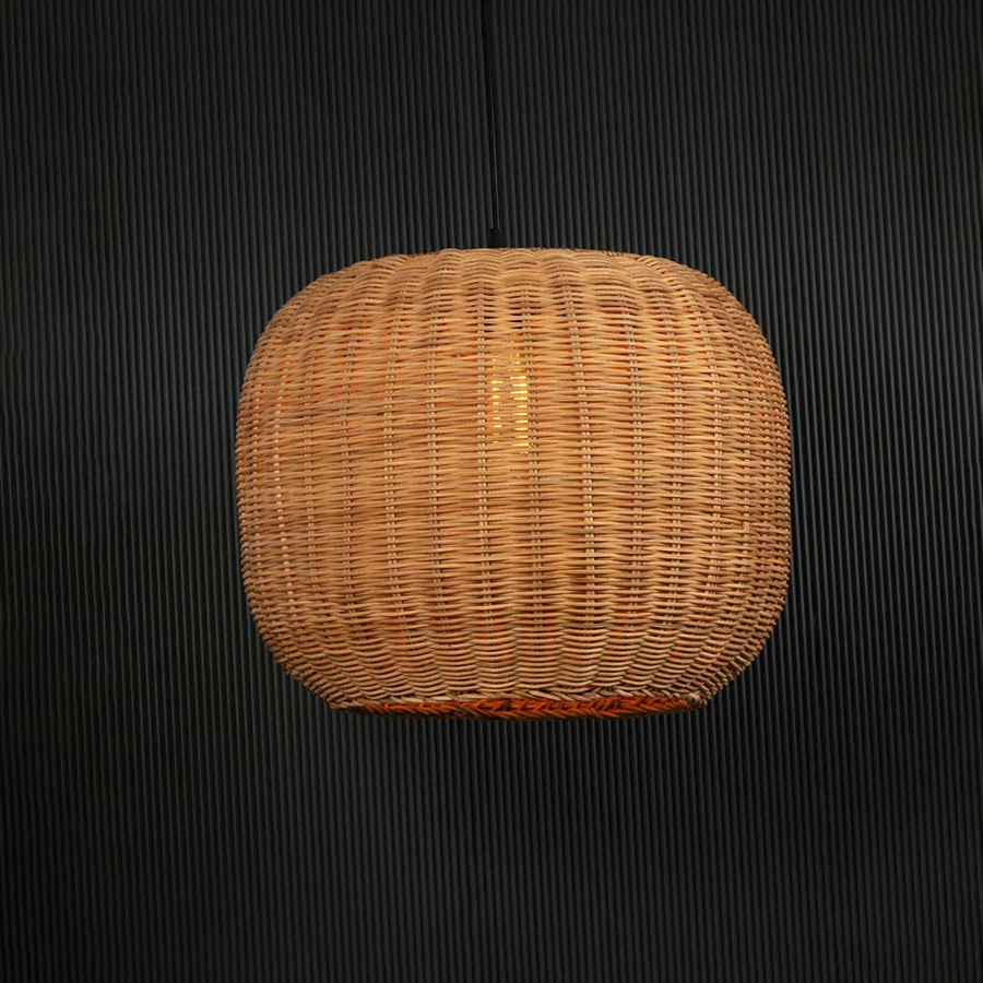 Round rattan pendant light glowing softly on black background creating a cozy ambient effect.