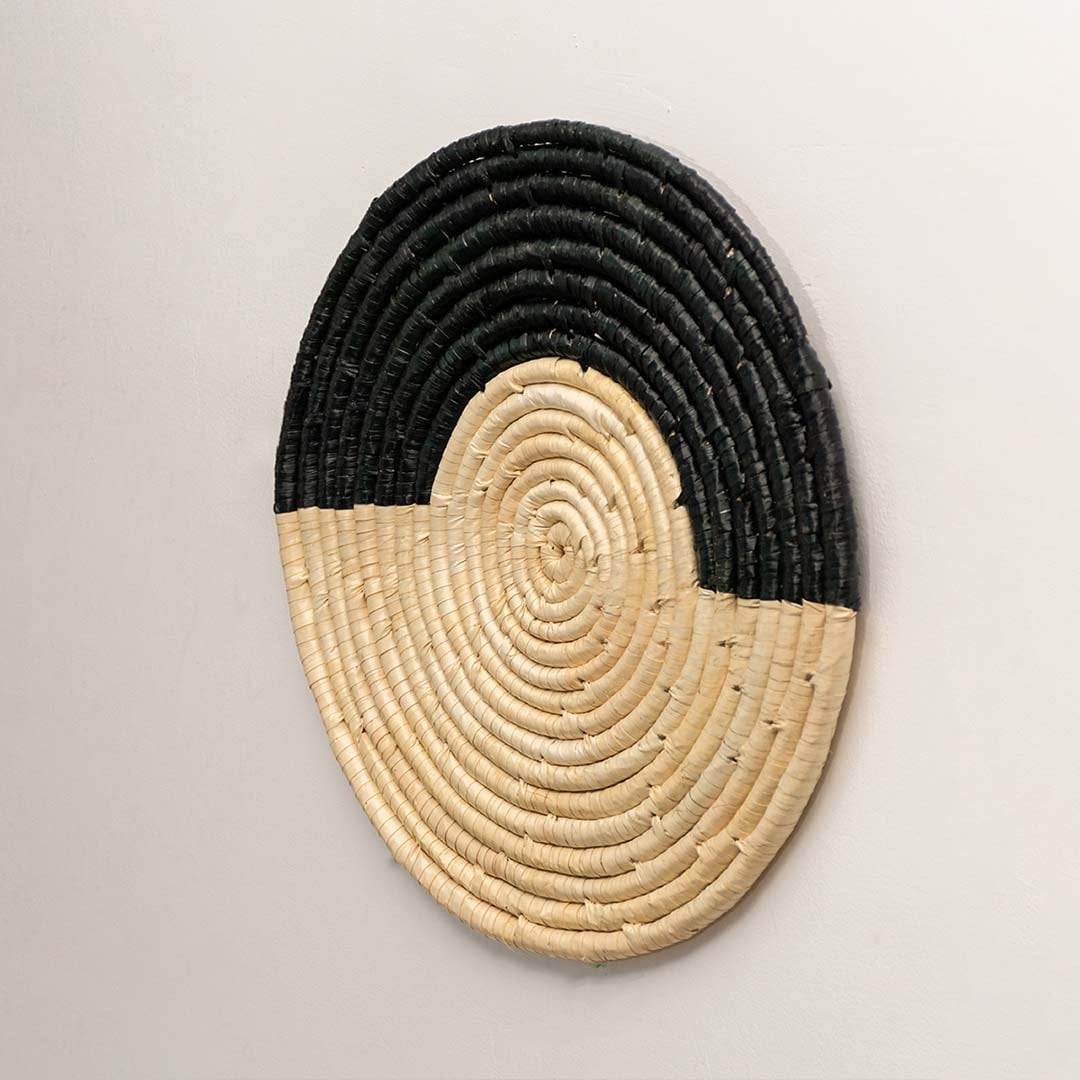 Side angle of round woven wall hanging showing depth texture and handcrafted spiral woven details.