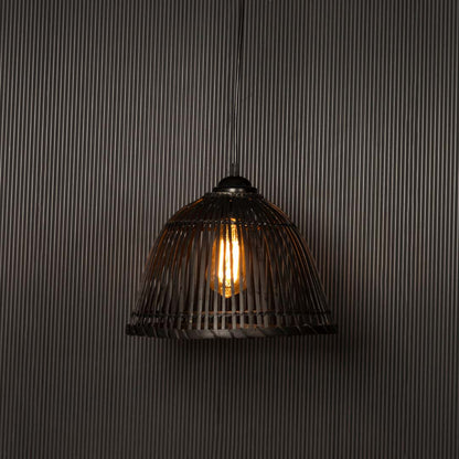 Black rattan hanging light glowing softly on dark background creating warm ambient lighting for home decor.