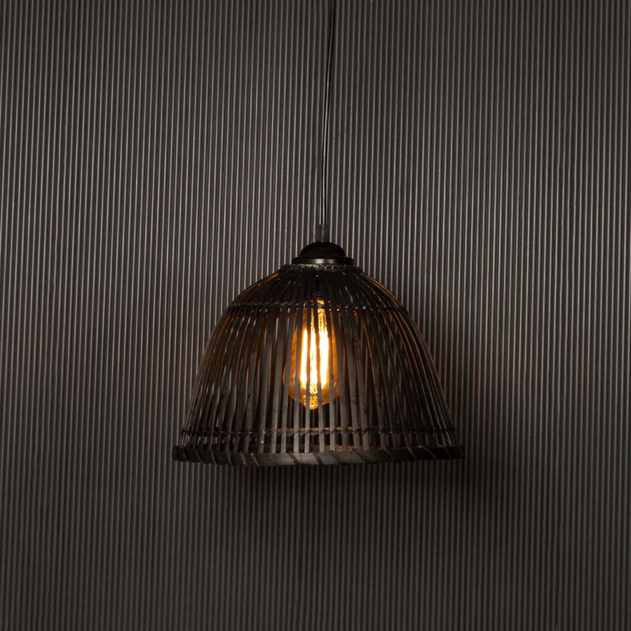 Black rattan hanging light glowing softly on dark background creating warm ambient lighting for home decor.