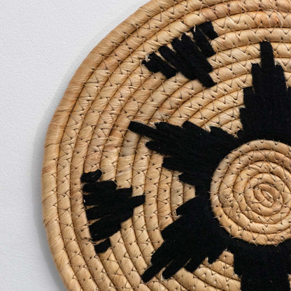 Detailed closeup view of the tight coil weaving and black wrapped star section on the natural seagrass wall basket surface quality.