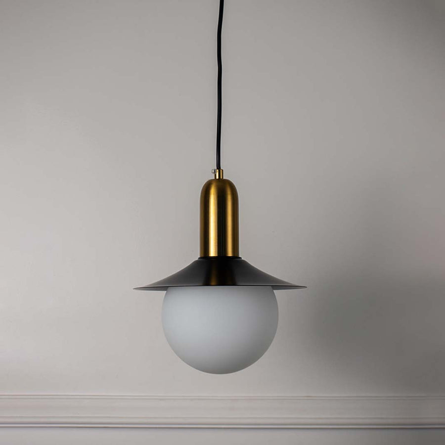 White glass pendant light with black metal shade and brass accents crafted for modern interiors.