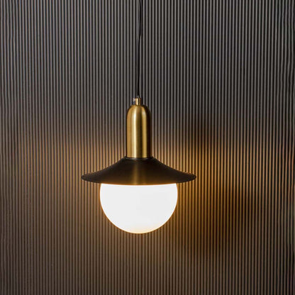 Black and brass dome pendant light with frosted glass globe glowing warmly on black background for stylish interiors.