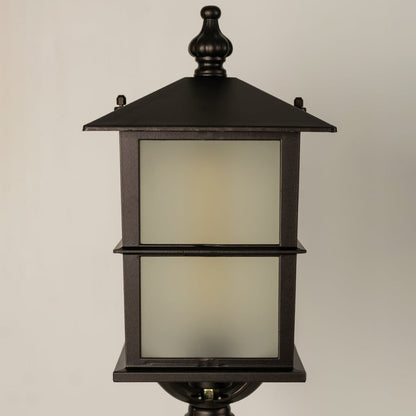 Closeup of a black outdoor pillar lamp showing glowing frosted glass and refined lantern edges designed for soft ambient garden and pathway lighting.