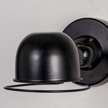 Black metal dome wall light with curved shade and wall mount on neutral background modern minimal lighting for interior decor.