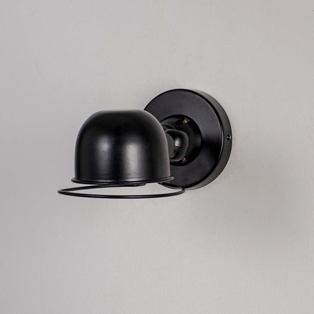 Wall sconce with matte black metal dome shade and cage detail perfect for bedroom living room and industrial style interiors.