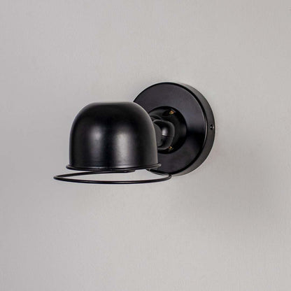 Wall sconce with matte black metal dome shade and cage detail perfect for bedroom living room and industrial style interiors.