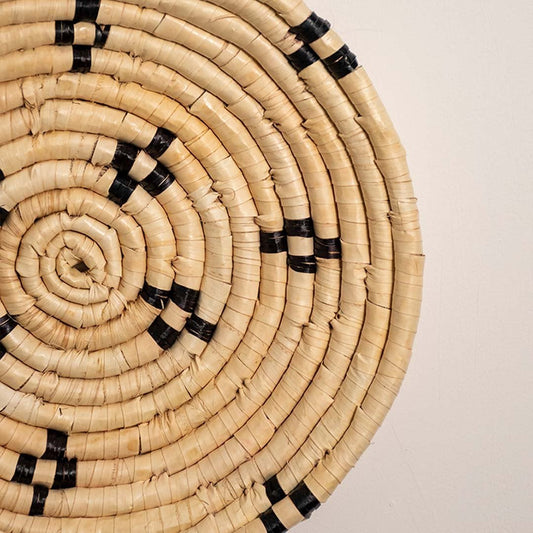 Detailed closeup view of the tight coil weaving and black stitched accents on the natural seagrass wall basket surface quality.