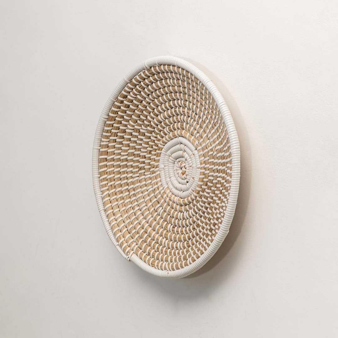A side angle of a beige and white wicker wall decor plate highlighting its raised woven structure and handcrafted natural fiber detailing.