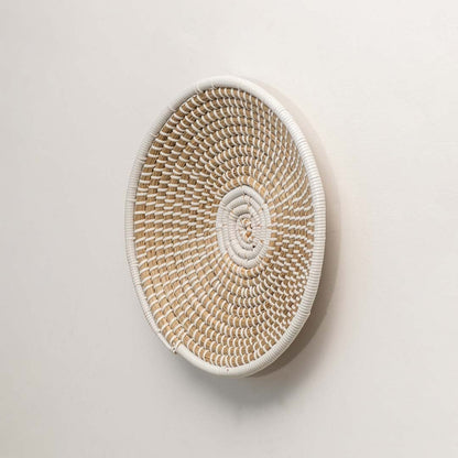A side angle of a beige and white wicker wall decor plate highlighting its raised woven structure and handcrafted natural fiber detailing.