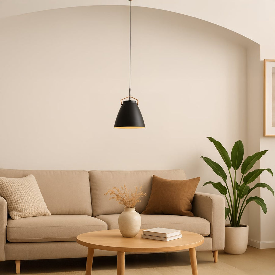 Black pendant light hanging above a cozy beige sofa in a modern living room with warm neutral tones.