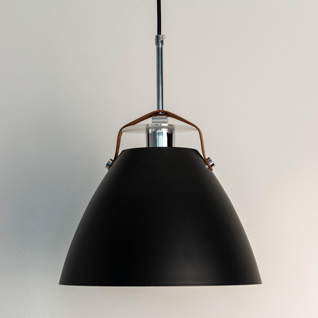 Black pendant light softly illuminated to emphasize smooth contours and minimalist structure.