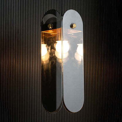 Grey glass pendant light displayed with light on against a dark background enhancing its warm illumination reflective finish and gold detailing.