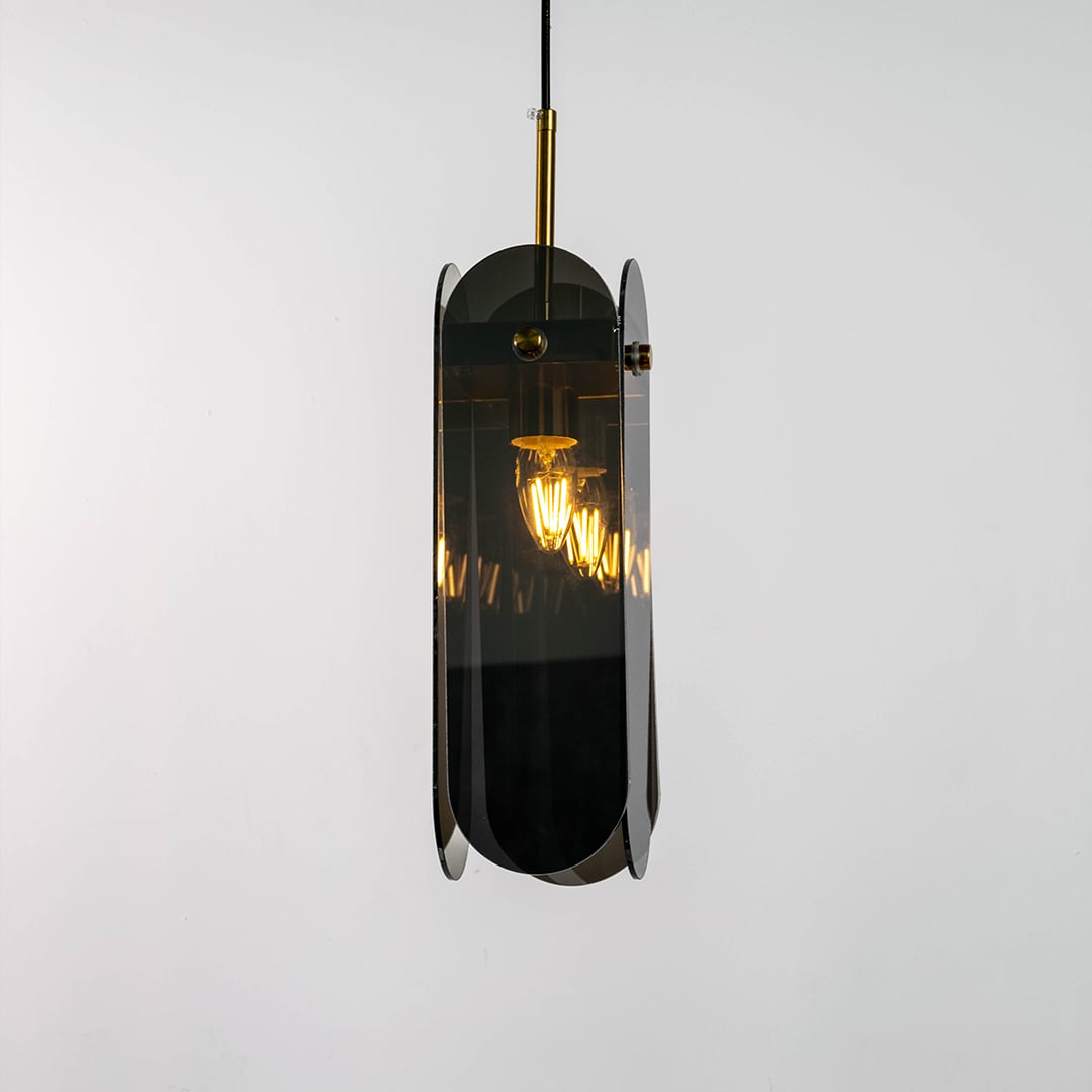 Grey glass pendant light displayed with light on against a dark background enhancing its warm illumination reflective finish and gold detailing.