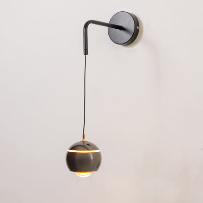 Modern wall light in black metal finish with hanging globe shade for bedroom or living decor lighting white background.