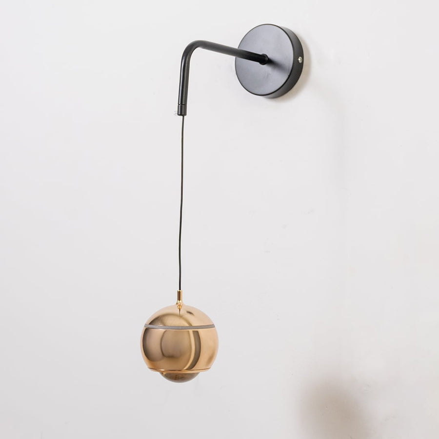Spherical gold wall light turned off shown on white background with modern metallic design style.