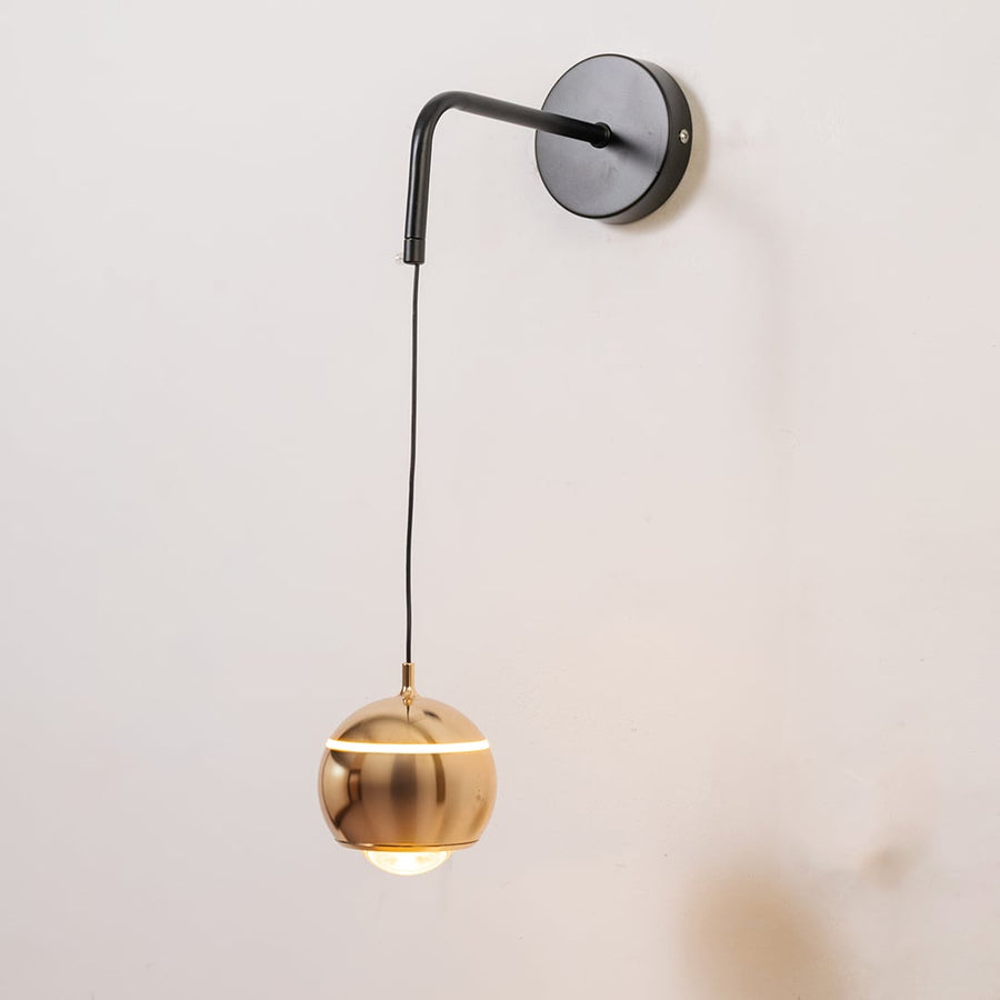 Spherical gold metal wall light turned on shown on white background for modern home and office decor.