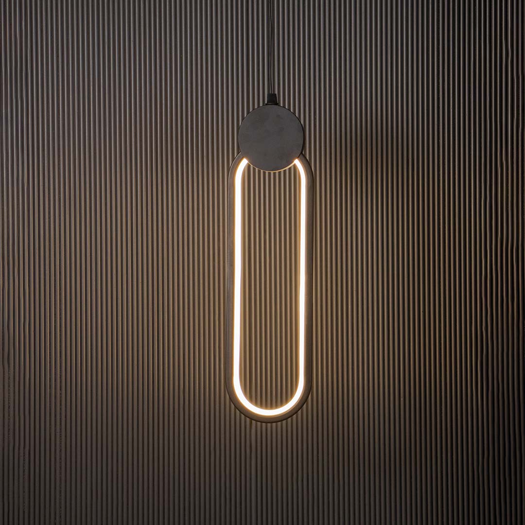 Modern slim oval black LED pendant light glowing brightly on black background ideal for elegant home interiors.