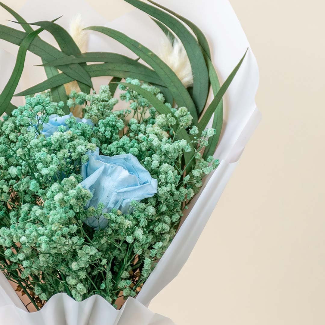 Closeup of dried flower bouquet with blue infinity rose preserved green babysbreath pampas grass and eucalyptus leaves.