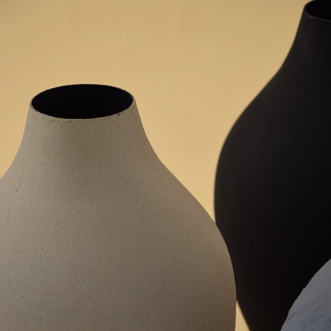 A detailed view of a sculpted textured vase highlighting its matte surface organic curves and handcrafted finish set against a soft warm toned background.