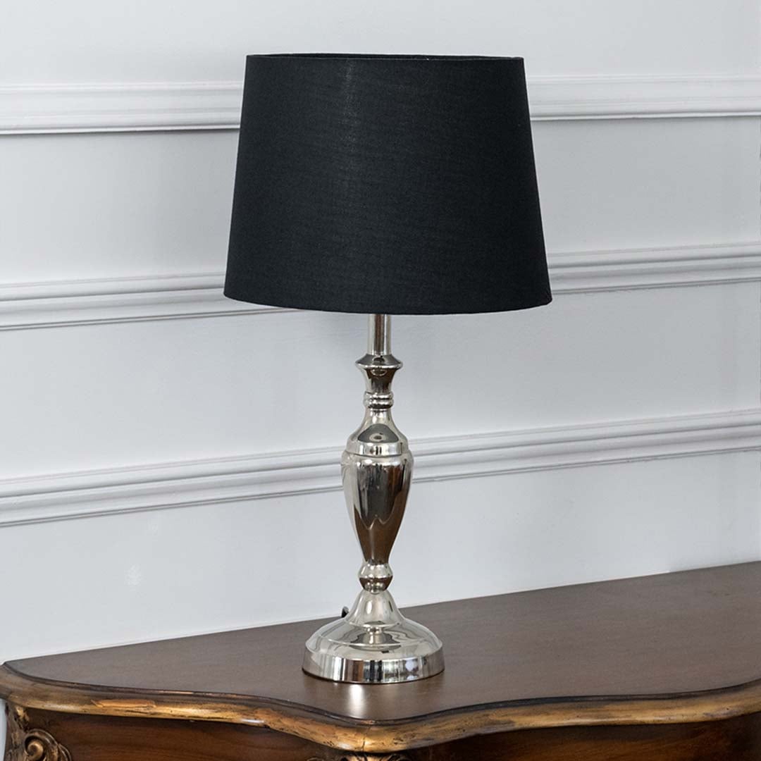 Black fabric shade table lamp with brass base glowing softly on a classic wooden side table adding a cozy ambiance.