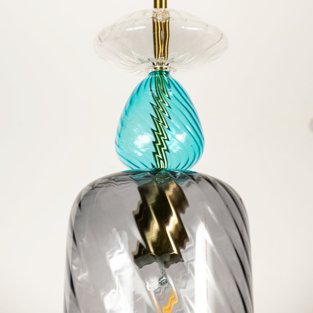 Close view of the pendant light showing grey blue glass texture and metallic accents creating an elegant handcrafted lighting statement piece.