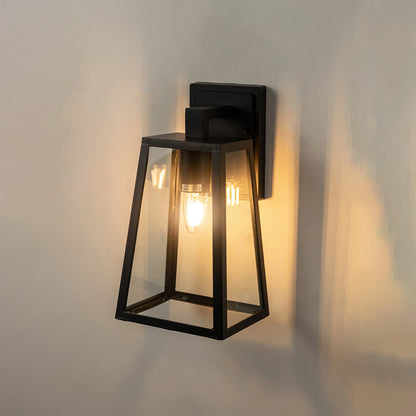 Black metal outdoor wall light glowing warmly on exterior wall for modern patio and entryway decor.