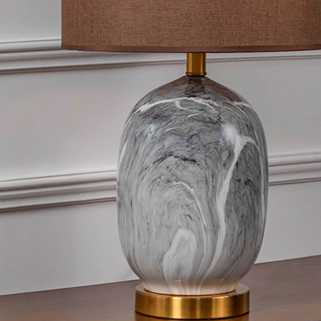 Closeup of grey marble finish table lamp with gold base and brown shade showing fine detailing.