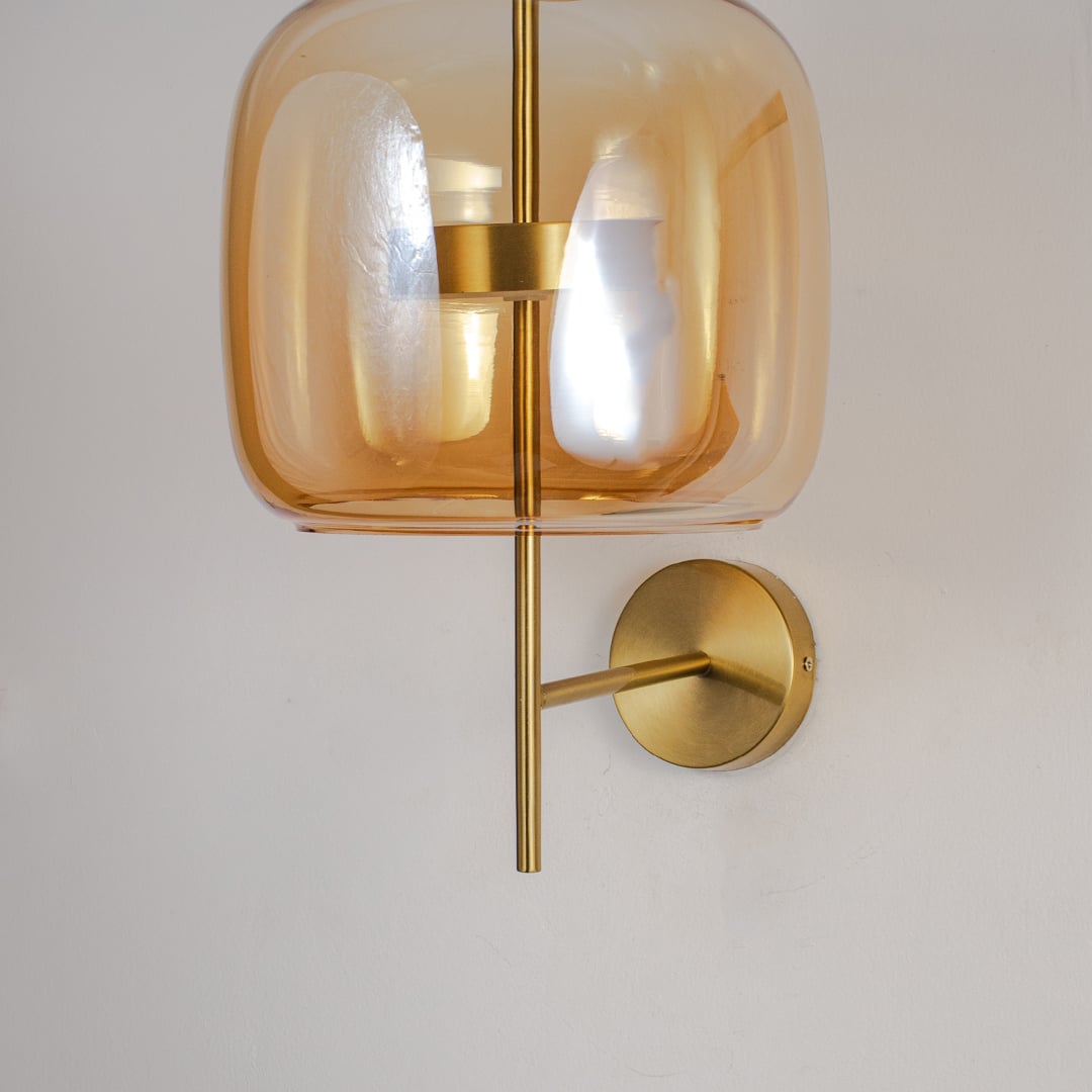 Closeup of amber glass and gold metal wall light for modern bedroom and premium decor styling spaces.