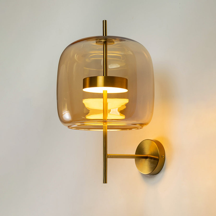 Modern wall light with gold mount and transparent glass shade on neutral background warm ambient lighting for bedroom decor.