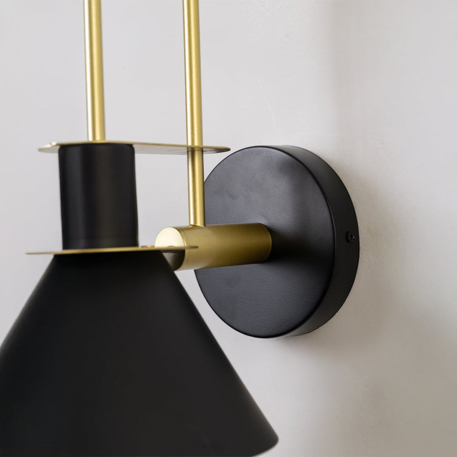 Closeup of black and gold wall light showing sleek conical shade and premium metal craftsmanship for interiors.