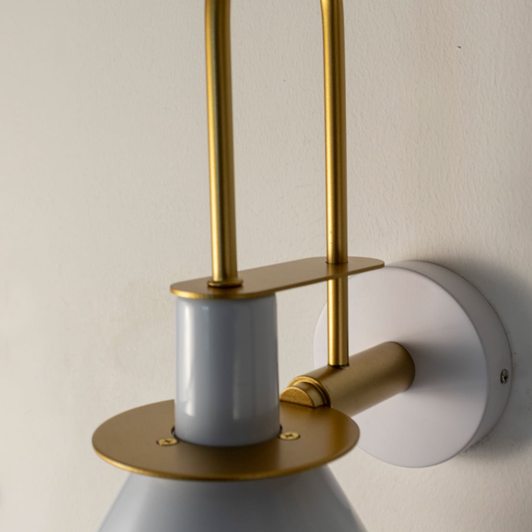 Closeup of white and gold wall sconce showing smooth metal finish and refined craftsmanship for luxury decor.
