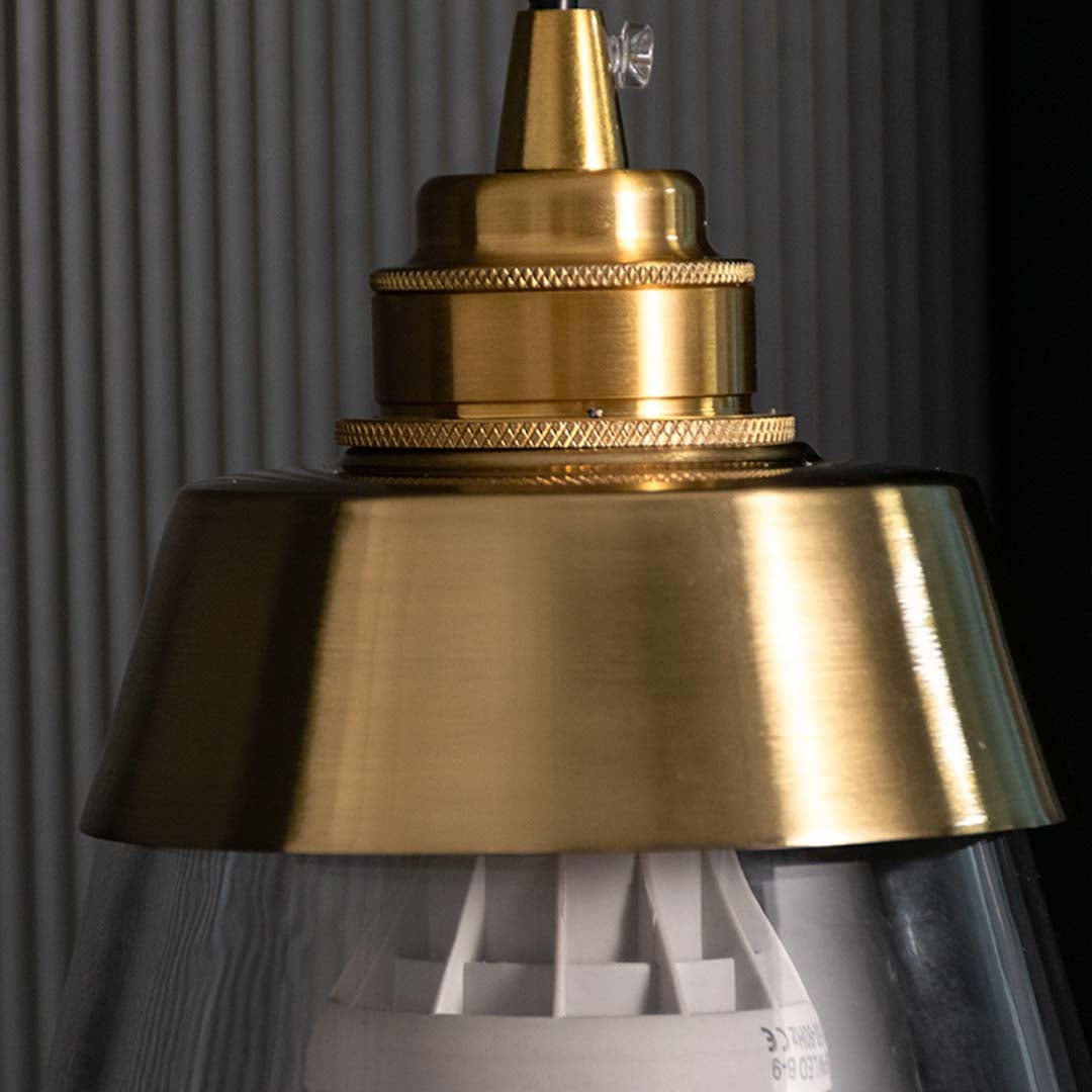 Detailed closeup of gold and clear glass pendant light highlighting its tapered shade and refined contemporary design.