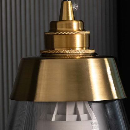 Detailed closeup of gold and clear glass pendant light highlighting its tapered shade and refined contemporary design.