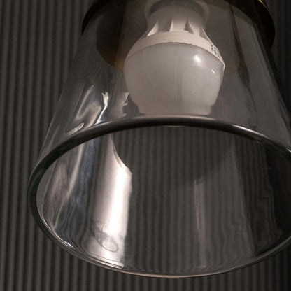 Closeup of clear glass cone pendant light showing polished gold metal accents and warm glow for modern decorative home lighting.