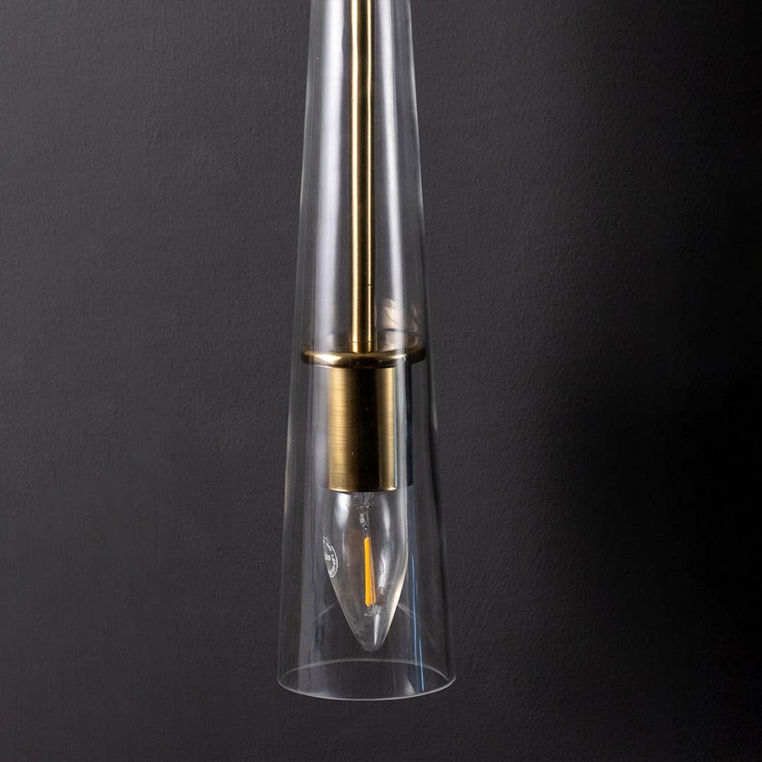 Detailed view of polished gold brass rod and clear tapered glass of modern hanging wall lamp showing high quality craftsmanship detail.