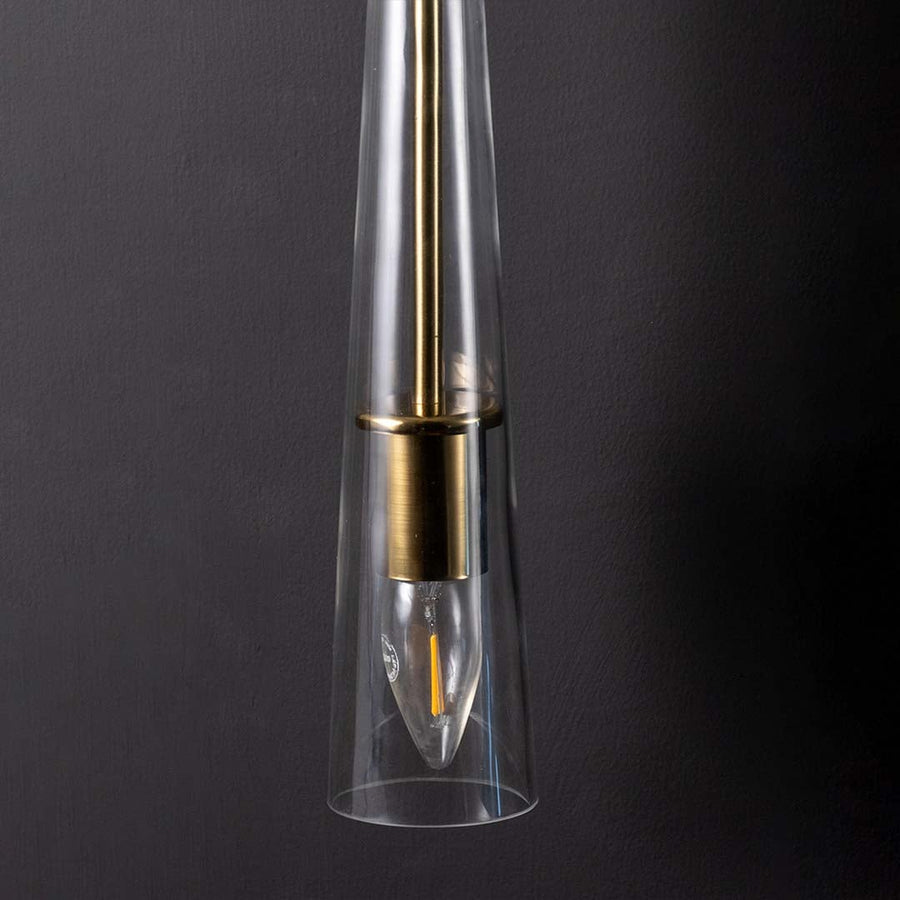 Detailed view of polished gold brass rod and clear tapered glass of modern hanging wall lamp showing high quality craftsmanship detail.
