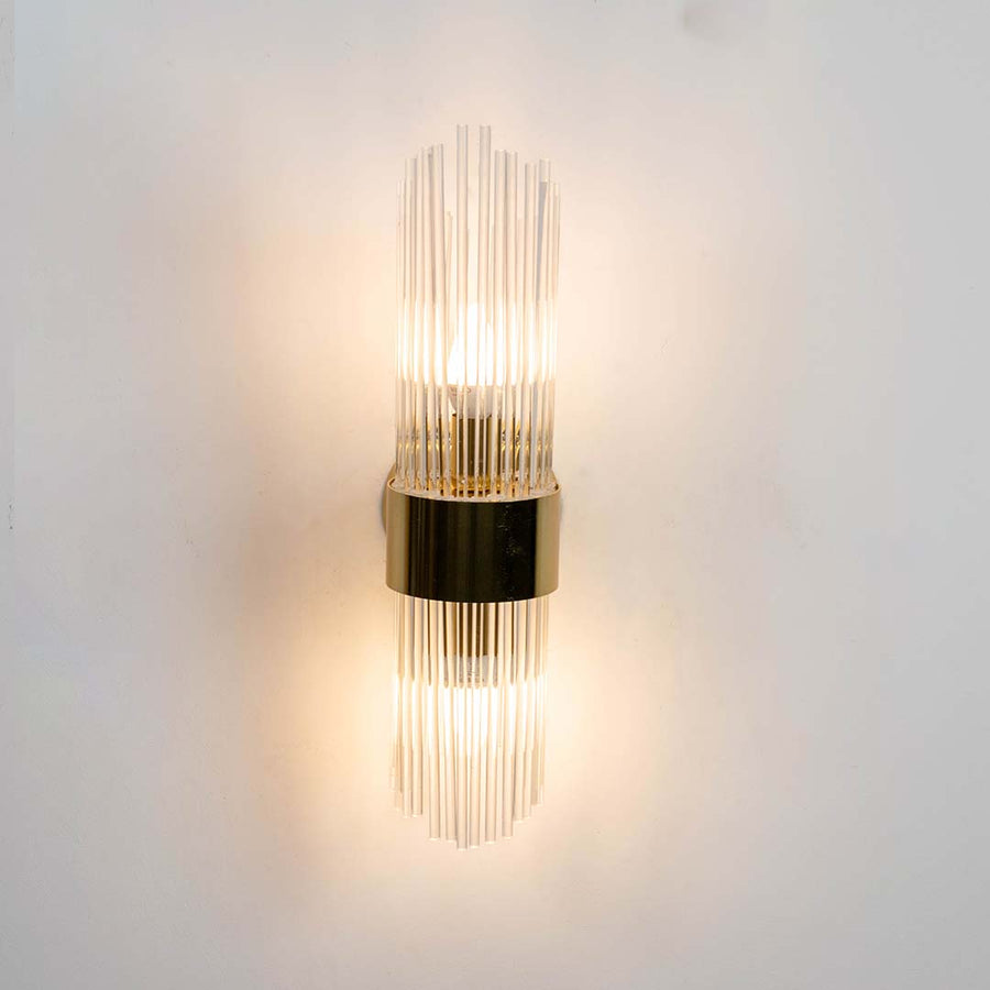 Metal and clear glass rod wall light shown with light on against a white background highlighting its warm illumination for home decor.