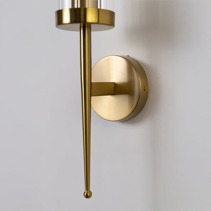 Elegant brass metal wall light with polished finish and clear glass shade for luxury interior decor.