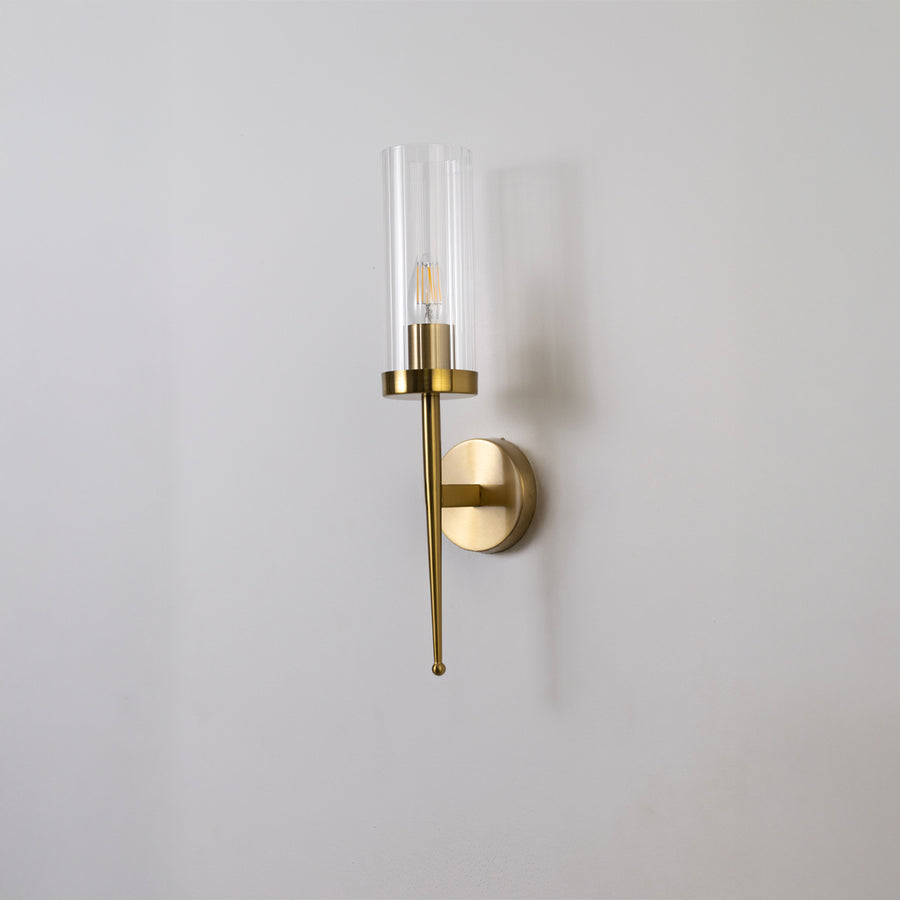 Contemporary brass wall light with sleek clear glass shade for stylish bedroom and hallway decor.