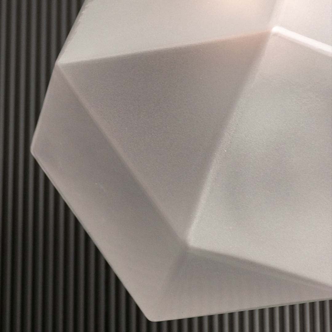 Closeup of frosted geometric pendant light showing textured faceted glass surface and warm inner glow for stylish ambient lighting.