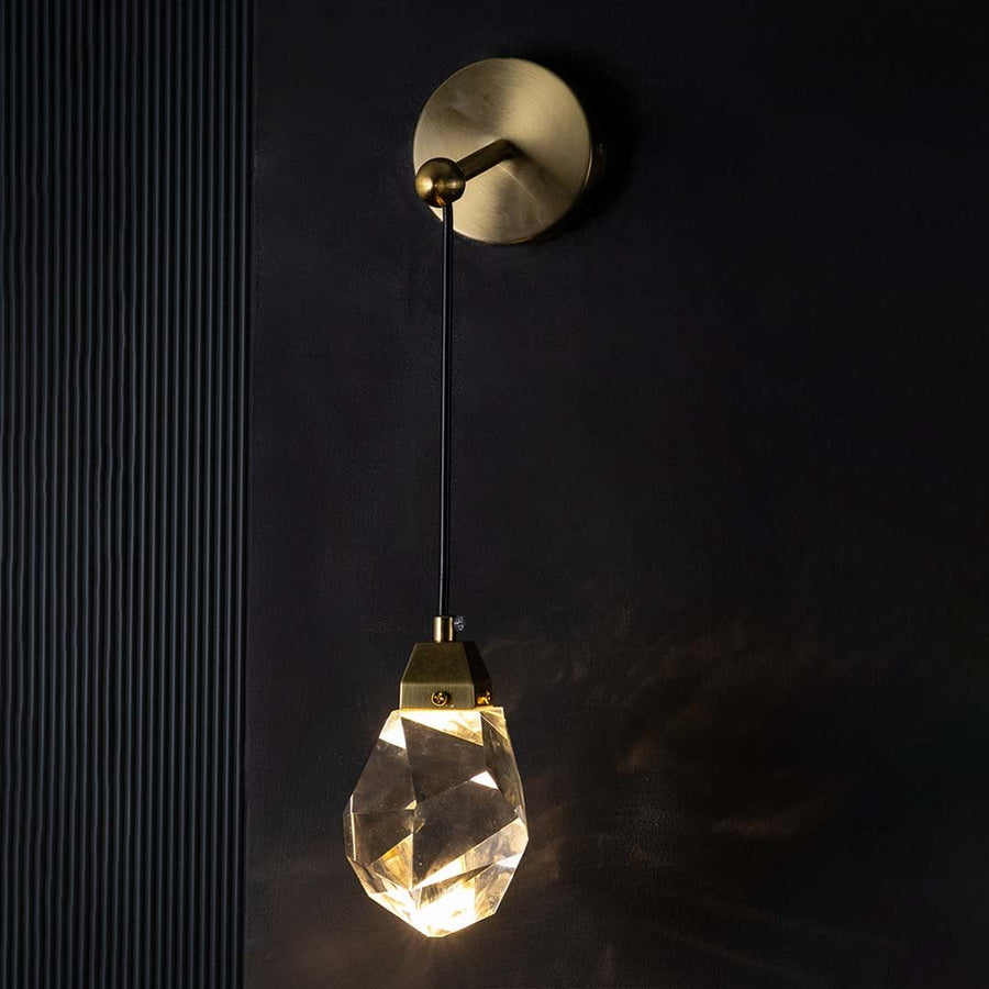 Gold and crystal pendant light glowing warmly on a dark background casting soft reflections and adding a luxurious modern lighting effect to interiors.