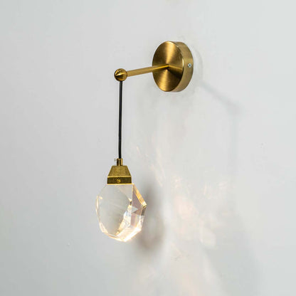 Crystal pendant light with gold metal cap switched on against a white background showing bright warm illumination and a premium faceted modern design.