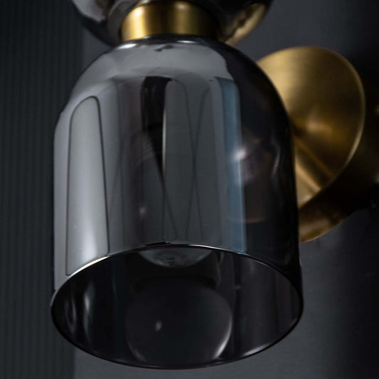 Close up details of a modern gold brass wall sconce featuring a smoky black translucent glass dome shade fixture.