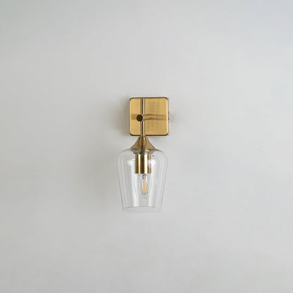Clear glass wall light with gold metal base displayed on a white background with the light off highlighting its modern minimalist shape and premium finish.